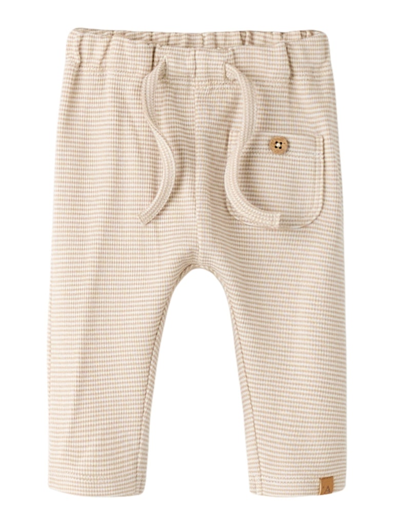 "Baby iført Lil’ Atelier NBMFENG Loose Pant – Oxford Tan, bløde jerseybukser med justerbar talje og løs pasform."