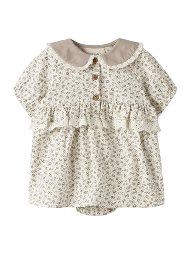 "Nyfødt barn iført Lil’ Atelier NBFFJOLA SS Loose Body Dress – Coconut Milk, korte ærmer, bedstefar-udskæring, loose fit, flæser og blondedetaljer, lavet af 100% økologisk bomuld, set forfra."