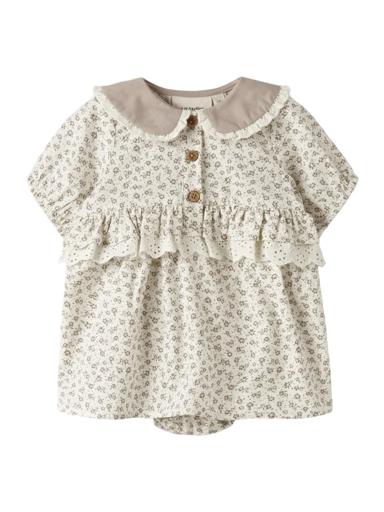 "Nyfødt barn iført Lil’ Atelier NBFFJOLA SS Loose Body Dress – Coconut Milk, korte ærmer, bedstefar-udskæring, loose fit, flæser og blondedetaljer, lavet af 100% økologisk bomuld, set forfra."