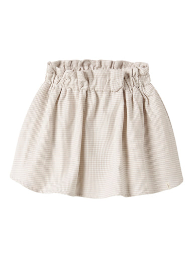"Barn iført Lil’ Atelier NMFFOLEY Skirt – Coconut Milk, nederdel i 100% økologisk bomuld med justerbar talje, set forfra."