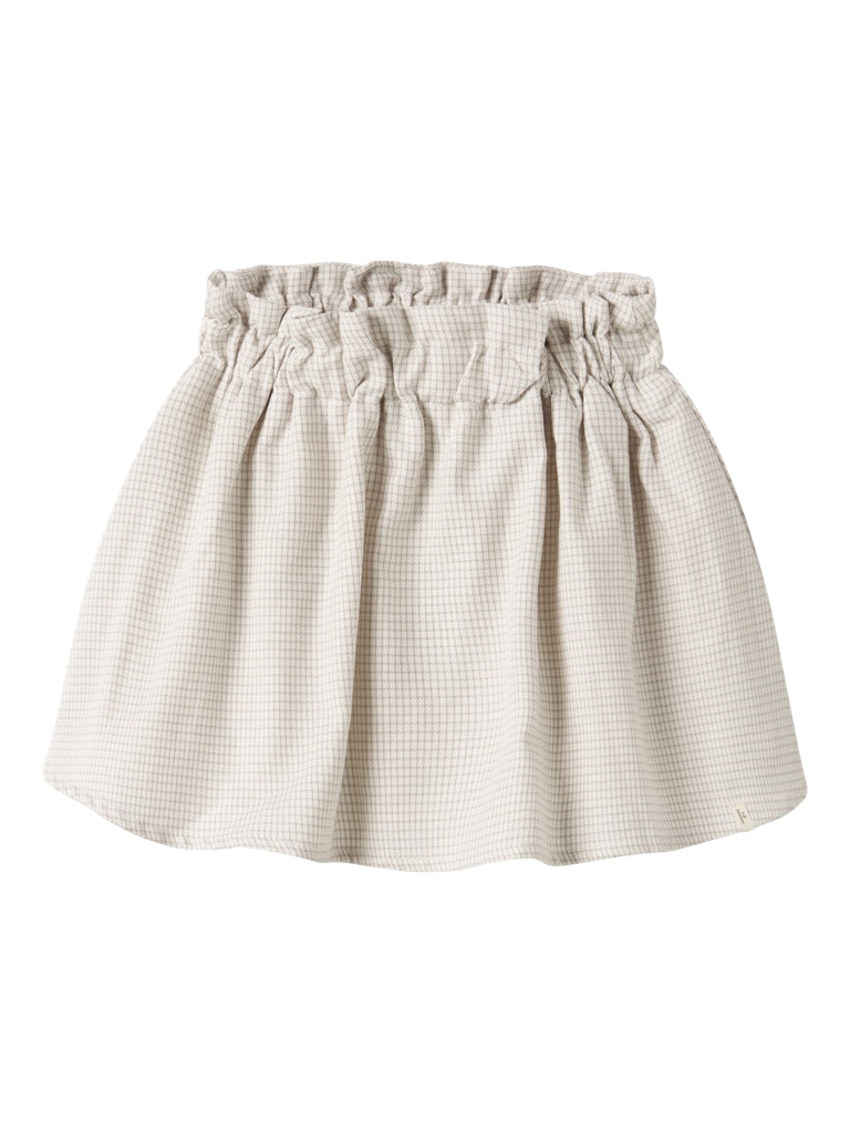 "Barn iført Lil’ Atelier NMFFOLEY Skirt – Coconut Milk, nederdel i 100% økologisk bomuld med justerbar talje, set forfra."