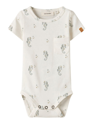 "Baby iført Lil’ Atelier NBMGAYO SEV SS Slim Body – Coconut Milk, kortærmet body i blød jersey med print og trykknapper."